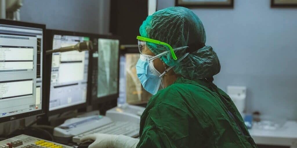 Healthcare professional in scrubs inputting data into a computer