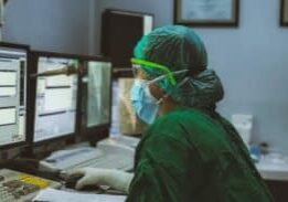 Healthcare professional in scrubs inputting data into a computer